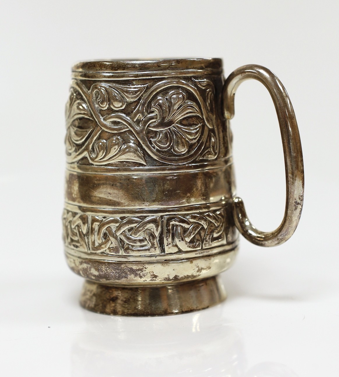 A George V embossed silver Iona mug, by Alexander Ritchie, Chester, 1911, with engraved initials, height 86mm, 1018 grams.